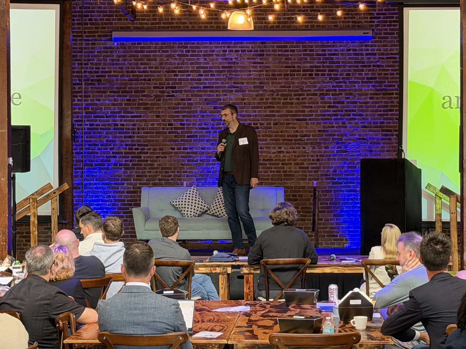 Jason Beutler speaking on stage at an evening venue event